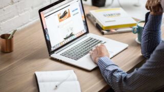 hand on laptop keyboard at desk