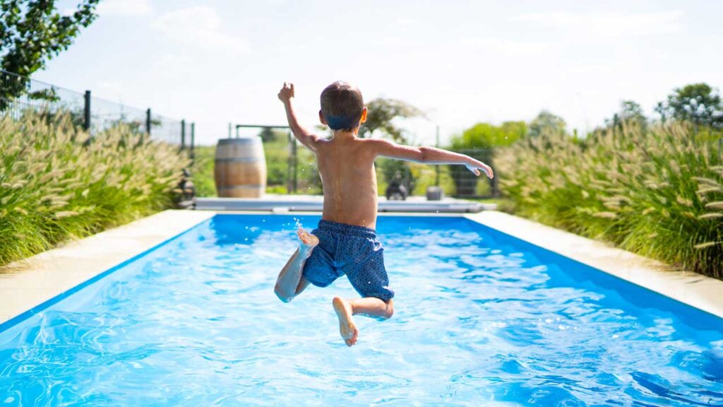 kid jumping into a blue pool