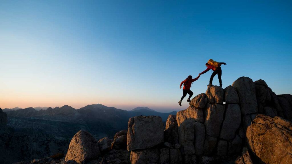 person helping another person up cliff