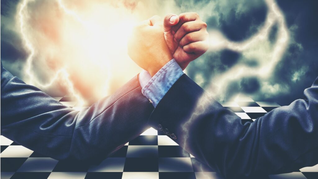 two hands arm wrestling on a chess board