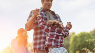 dad swinging child and both wearing plaid