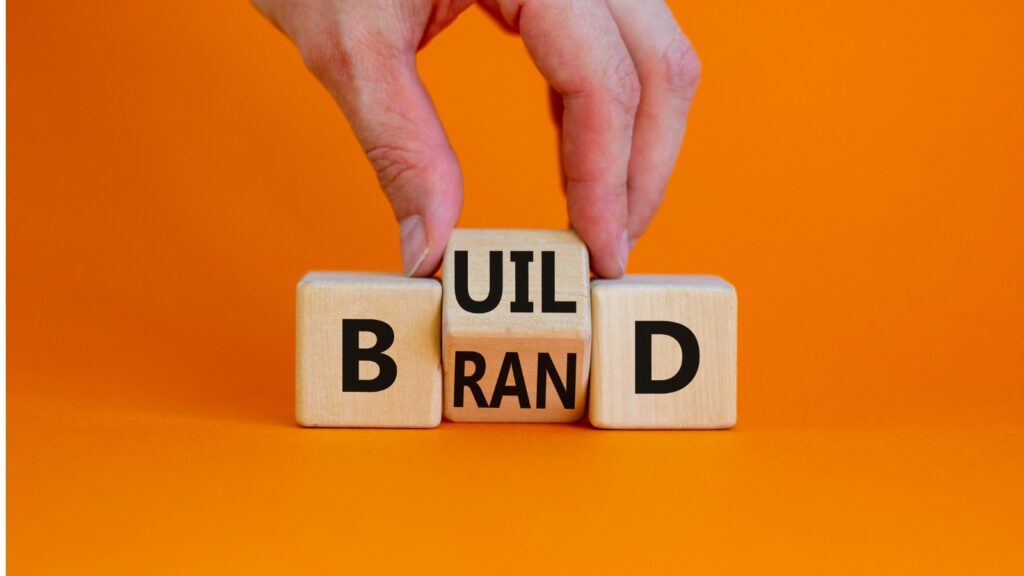 Build your brand symbol. Businessman turns wooden cubes and changes the word 'build' to 'brand'.