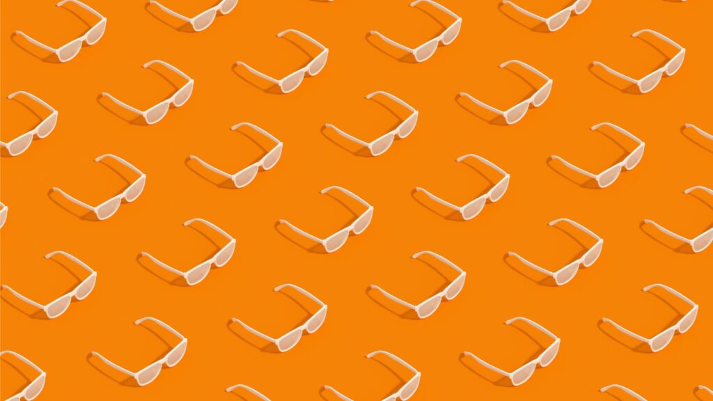 pattern of white rayban looking glasses on an orange background