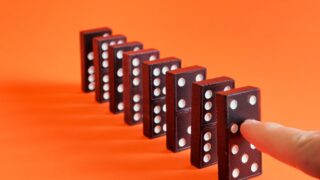 image of a finger about to topple dominos