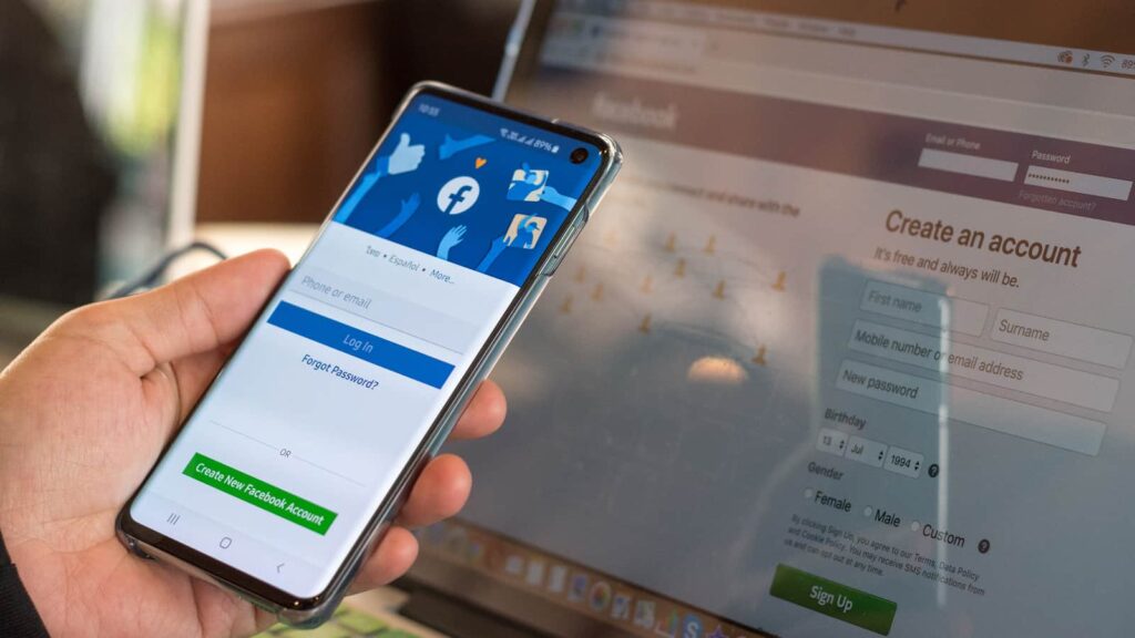 Facebook signup web page app on smart phone Samsung Galaxy S10 with user sign in registration screen using social networking and computer notebook from anywhere office.