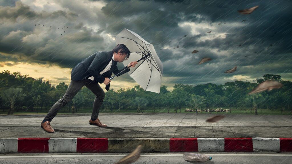 Businessman with white umbrella protecting himself from the storm.