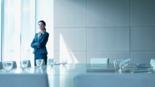 Businesswoman standing alone in conference room stock photo