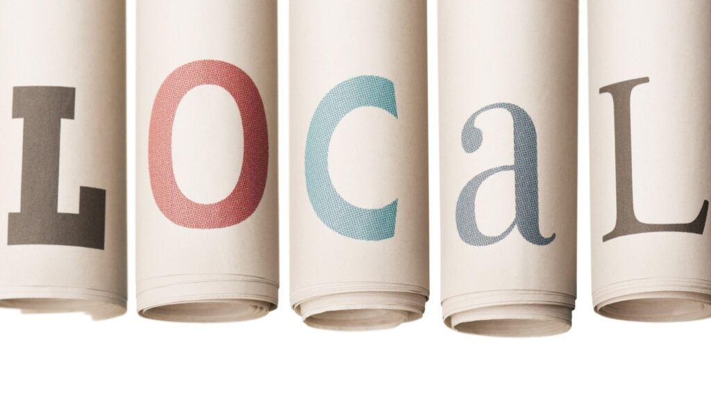 LOCAL news on rolled-up newspapers stock photo